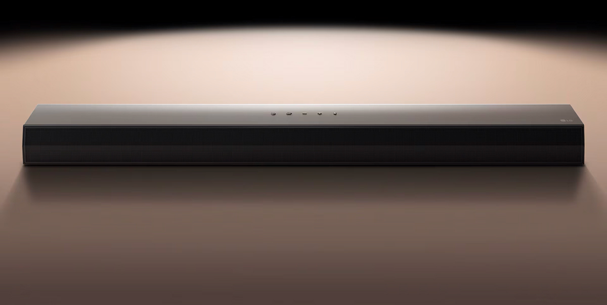 LG Soundbar μπροστά από μαύρο φόντο που φωτίζεται με προβολέα.